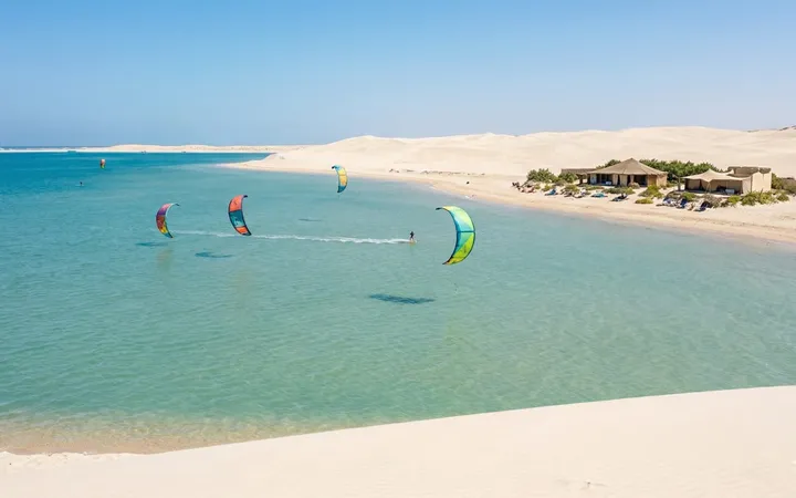 Lagune turquoise de Dakhla bordée de dunes blanches, avec des kitesurfeurs sur l'eau